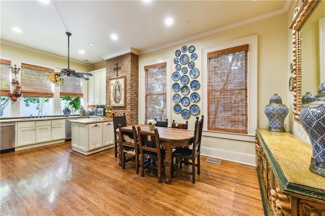 dining space with ornamental molding, sink, and light wood-type flooring