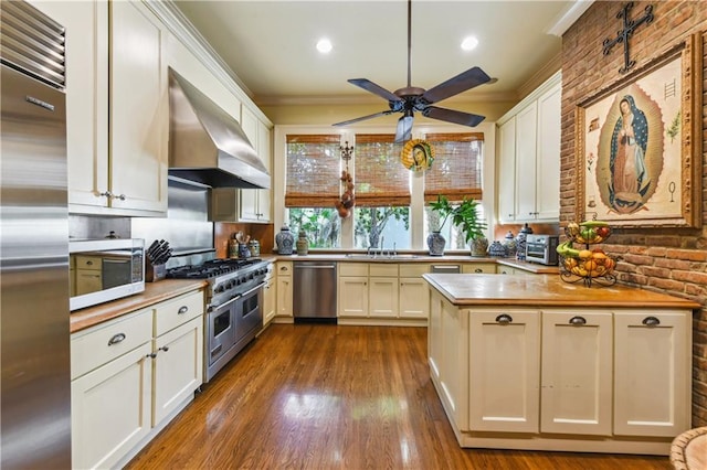 kitchen featuring white cabinetry, crown molding, wall chimney exhaust hood, and appliances with stainless steel finishes