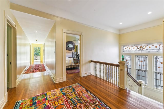 hallway with dark wood-type flooring and crown molding