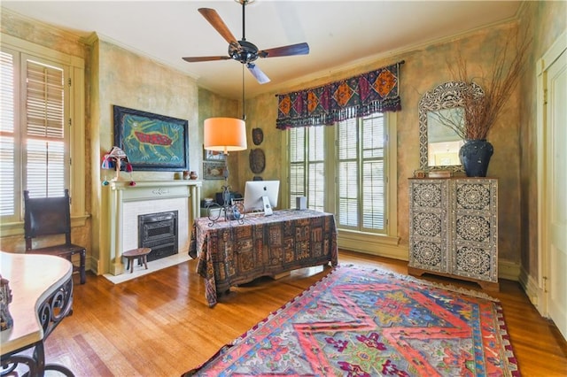 office area featuring crown molding, ceiling fan, a fireplace, and hardwood / wood-style flooring