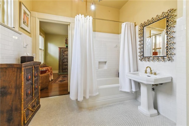 bathroom with tile walls, tile patterned flooring, and shower / bath combo with shower curtain