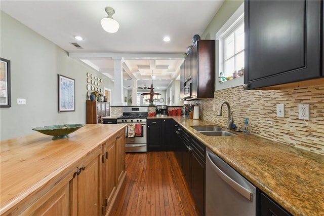 kitchen with light stone counters, stainless steel appliances, sink, and backsplash