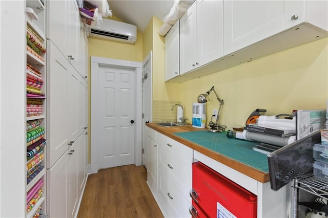 kitchen with dark hardwood / wood-style floors, a wall mounted AC, sink, and white cabinets