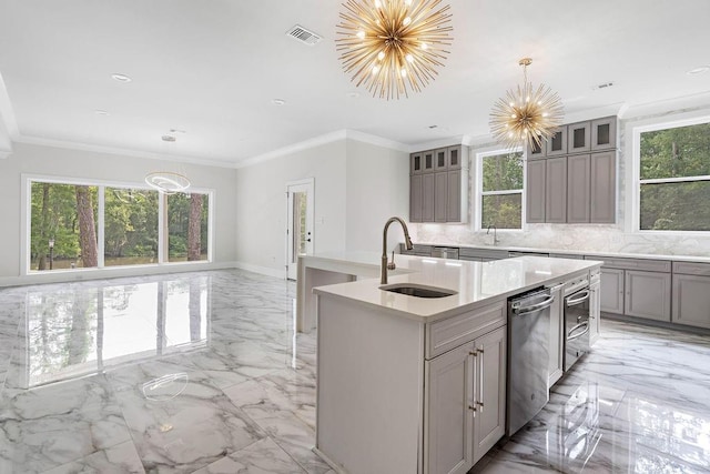 kitchen featuring decorative light fixtures, sink, ornamental molding, a notable chandelier, and a center island with sink