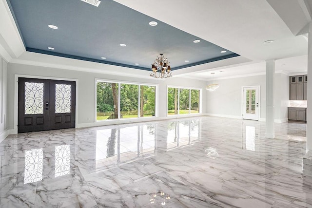 interior space with an inviting chandelier, a tray ceiling, crown molding, and french doors