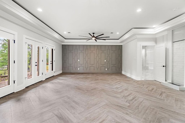 spare room featuring crown molding, a wealth of natural light, a raised ceiling, and light parquet floors