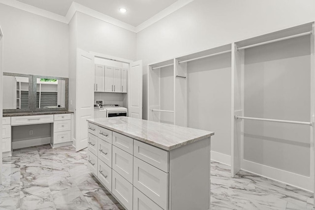 spacious closet with built in desk, washing machine and clothes dryer, and a high ceiling