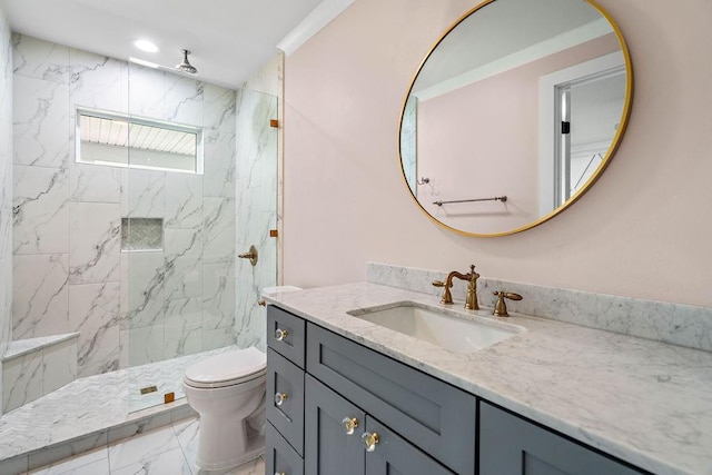 bathroom with tiled shower, vanity, and toilet