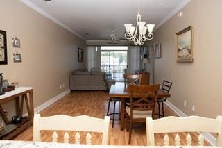 dining room with an inviting chandelier, crown molding, and light wood-type flooring