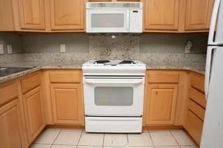 kitchen with light tile patterned floors, white appliances, and sink