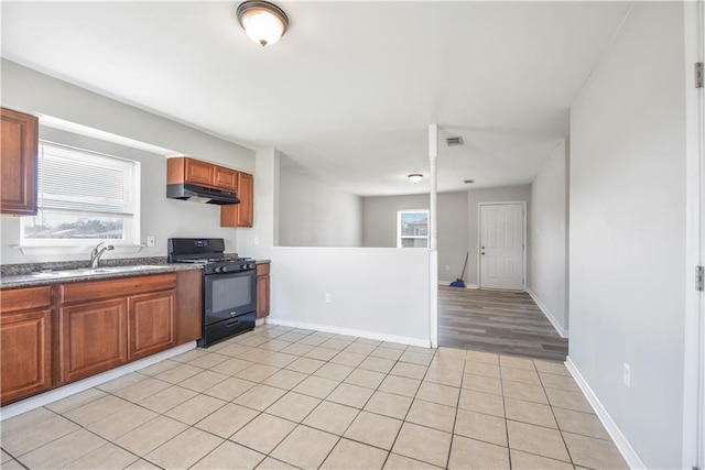 kitchen featuring light tile patterned floors, sink, and black gas range oven