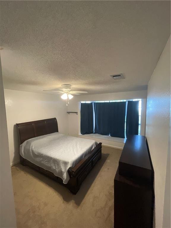 bedroom with ceiling fan, carpet floors, and a textured ceiling