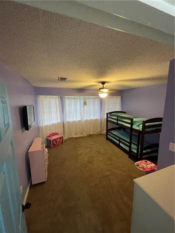 carpeted bedroom featuring ceiling fan and a textured ceiling