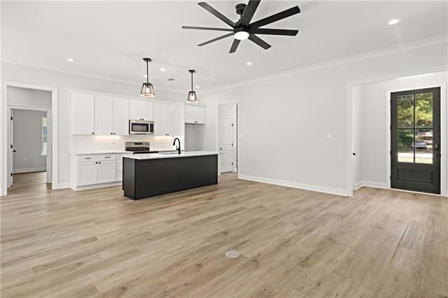 kitchen with crown molding, appliances with stainless steel finishes, white cabinetry, hanging light fixtures, and an island with sink