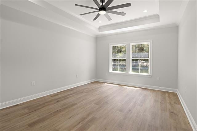 unfurnished room featuring a raised ceiling, crown molding, hardwood / wood-style floors, and ceiling fan