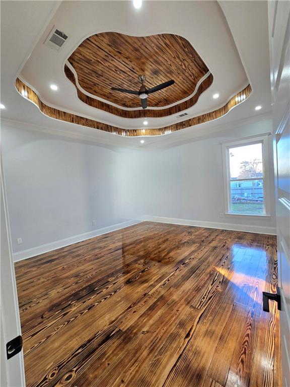 spare room featuring a raised ceiling, hardwood / wood-style flooring, and ceiling fan