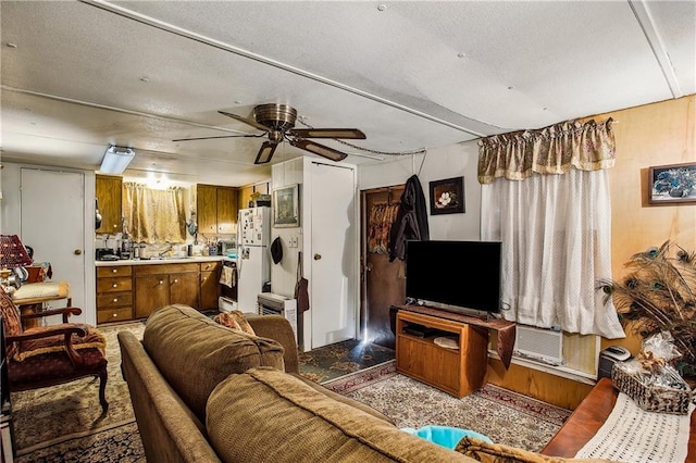 living room featuring ceiling fan and a textured ceiling