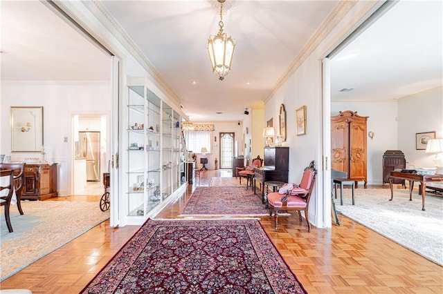 corridor featuring crown molding, a chandelier, and light parquet floors