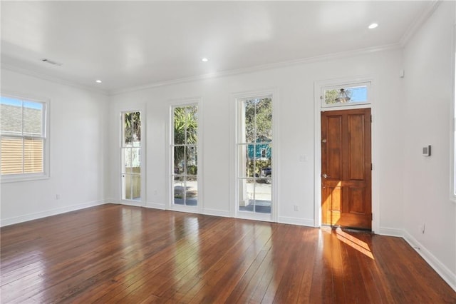 empty room featuring visible vents, baseboards, crown molding, and hardwood / wood-style flooring