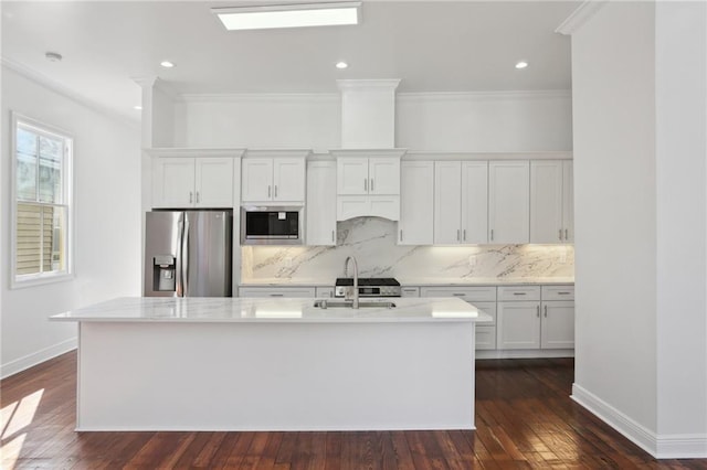 kitchen with tasteful backsplash, a sink, baseboards, appliances with stainless steel finishes, and a kitchen island with sink