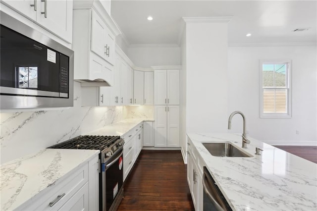 kitchen featuring ornamental molding, appliances with stainless steel finishes, white cabinetry, and a sink