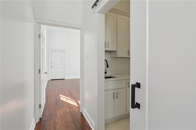 hallway with a sink, baseboards, and wood finished floors