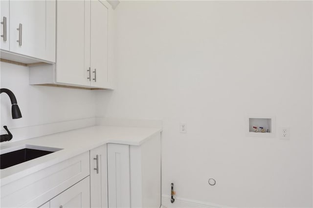 clothes washing area with baseboards, cabinet space, a sink, washer hookup, and hookup for a gas dryer