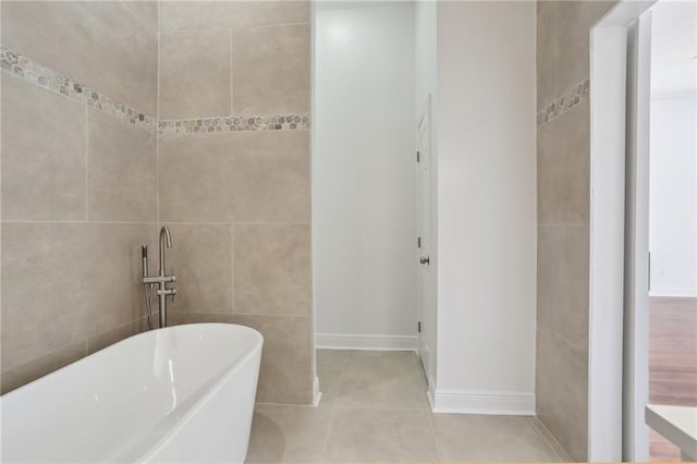 full bath featuring tile patterned flooring, tile walls, and a freestanding tub