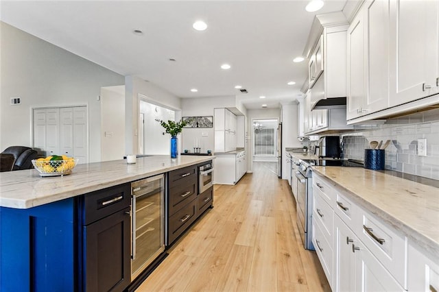 kitchen featuring white cabinetry, tasteful backsplash, stainless steel electric range oven, light stone counters, and beverage cooler