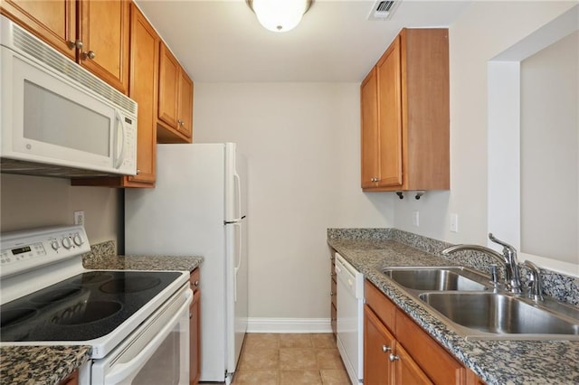 kitchen with sink, white appliances, and dark stone counters