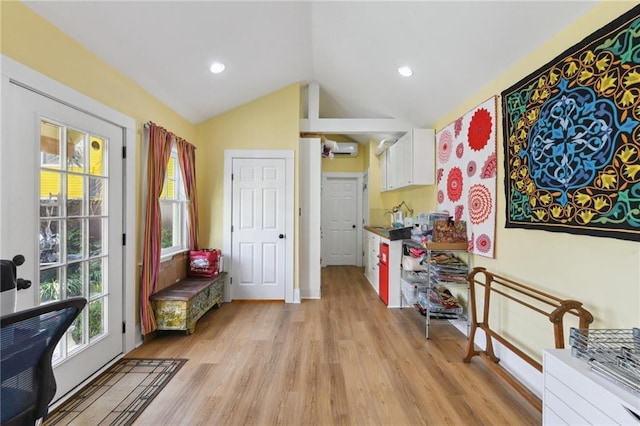 interior space with an AC wall unit, lofted ceiling, and light hardwood / wood-style flooring