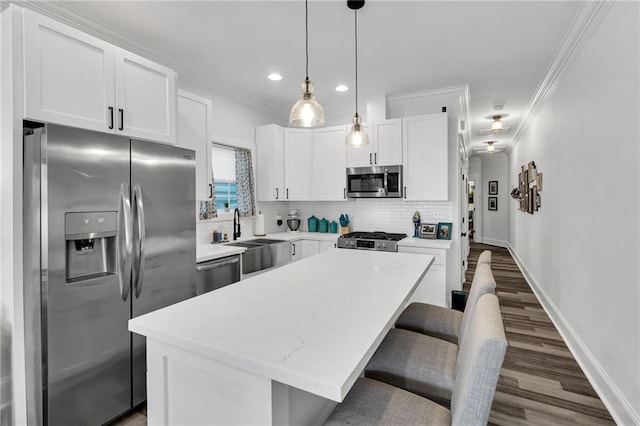 kitchen featuring white cabinets, decorative backsplash, hanging light fixtures, a center island, and stainless steel appliances