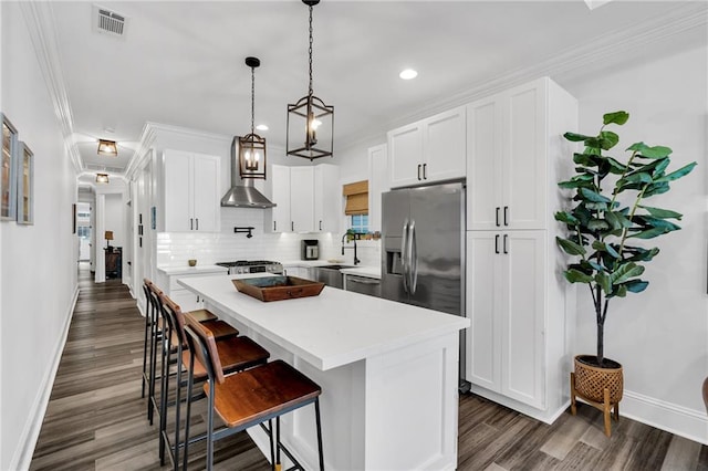 kitchen with backsplash, a kitchen island, stainless steel appliances, white cabinets, and a kitchen bar