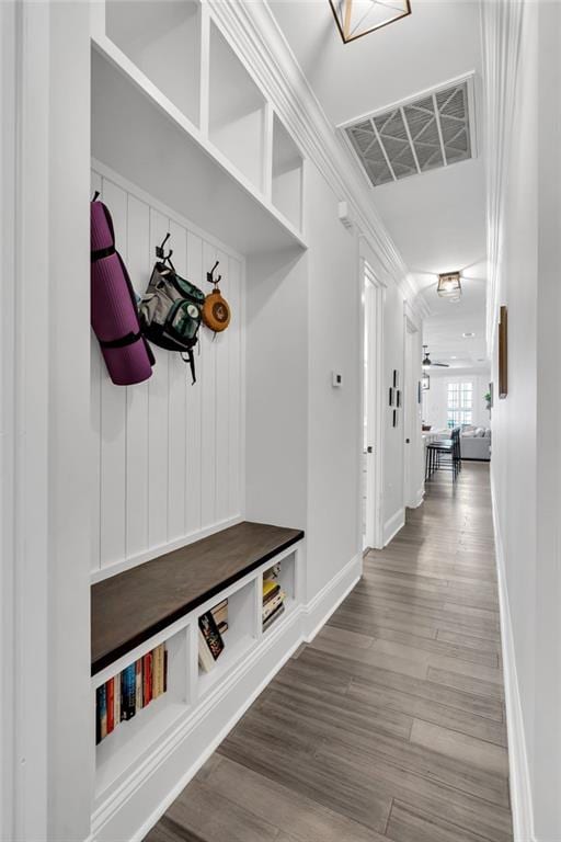 mudroom featuring ornamental molding, wood finished floors, visible vents, and baseboards