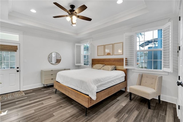 bedroom with crown molding, wood-type flooring, a raised ceiling, and multiple windows