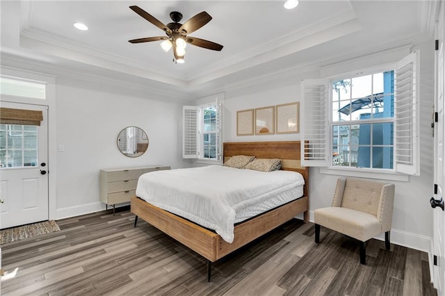 bedroom with a raised ceiling, crown molding, multiple windows, and wood finished floors