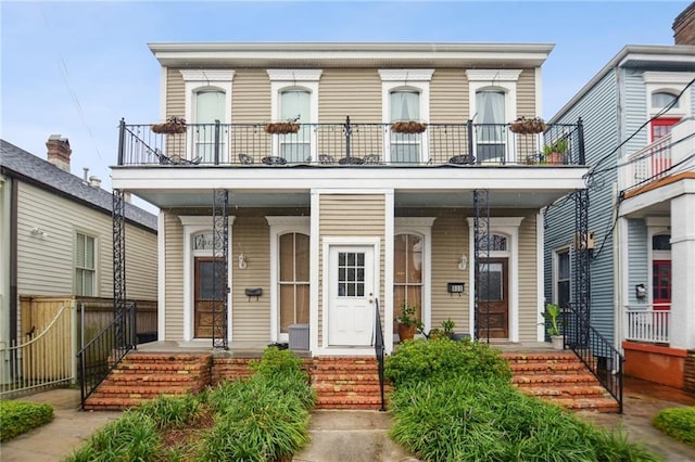 view of front of house with a balcony, fence, and a porch