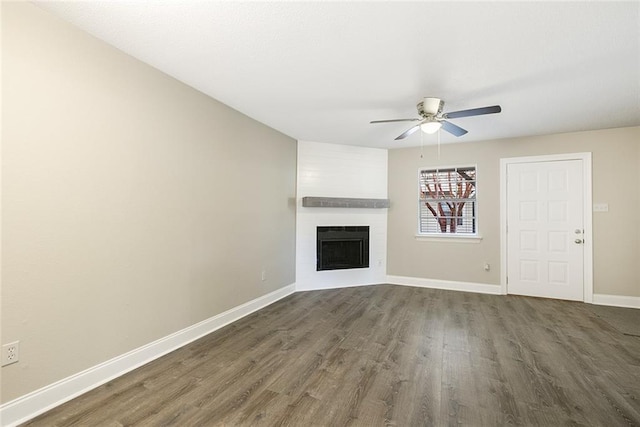 unfurnished living room featuring ceiling fan, a large fireplace, and dark hardwood / wood-style flooring