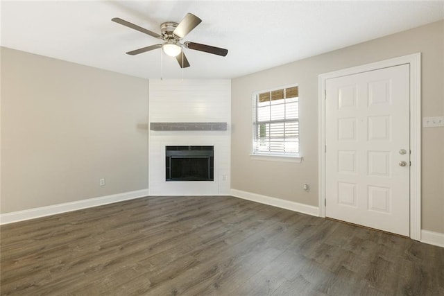 unfurnished living room featuring a large fireplace, dark hardwood / wood-style floors, and ceiling fan