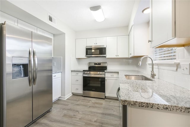 kitchen featuring light stone counters, appliances with stainless steel finishes, and white cabinets