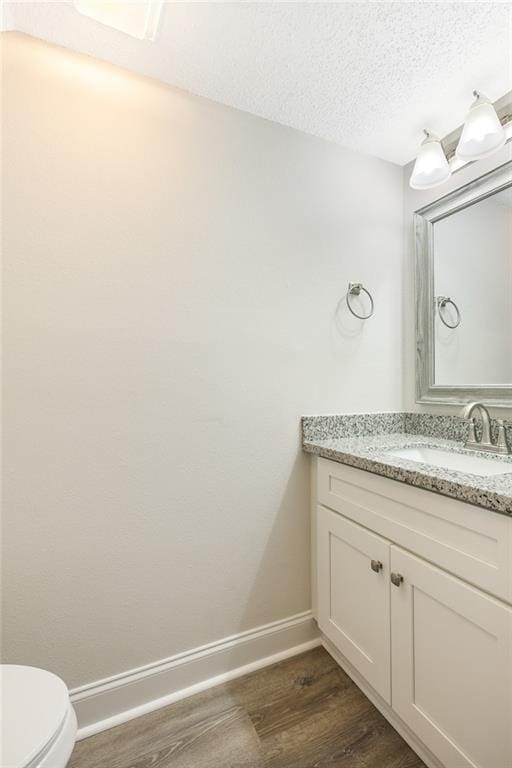 bathroom with vanity, hardwood / wood-style floors, a textured ceiling, and toilet