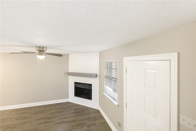 unfurnished living room featuring dark hardwood / wood-style flooring, ceiling fan, and a textured ceiling