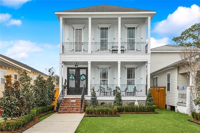 view of front of house featuring a balcony, a front lawn, covered porch, and french doors