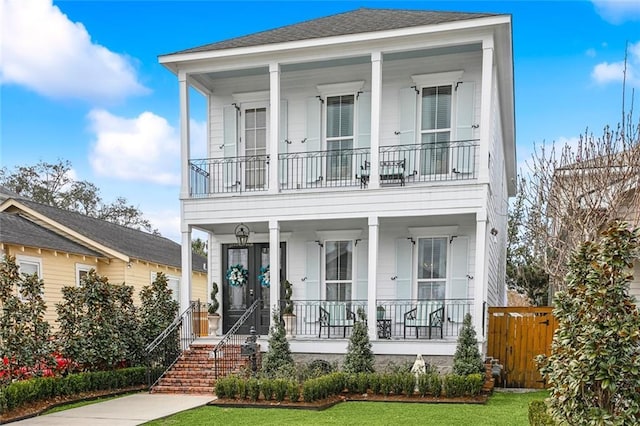 view of front facade featuring a balcony, covered porch, and a front yard