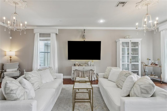 living room with wood-type flooring, crown molding, and an inviting chandelier