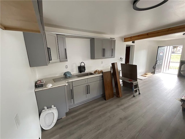 kitchen with beamed ceiling, sink, hardwood / wood-style floors, and gray cabinetry