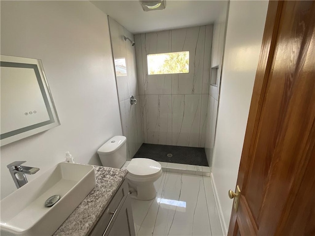 bathroom featuring vanity, tiled shower, and toilet