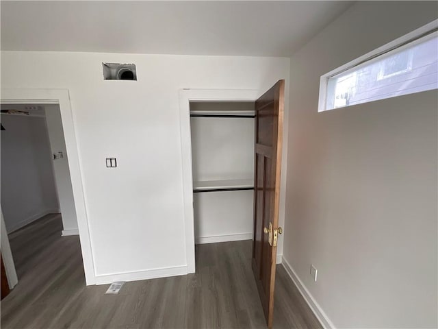 unfurnished bedroom with dark wood-type flooring and a closet