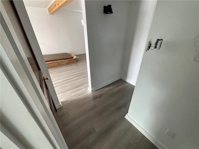 hall featuring dark wood-type flooring and beamed ceiling