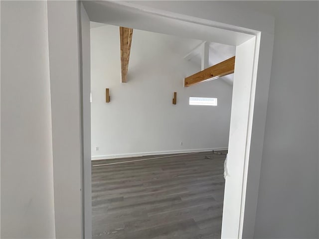 unfurnished room featuring dark wood-type flooring and vaulted ceiling with beams